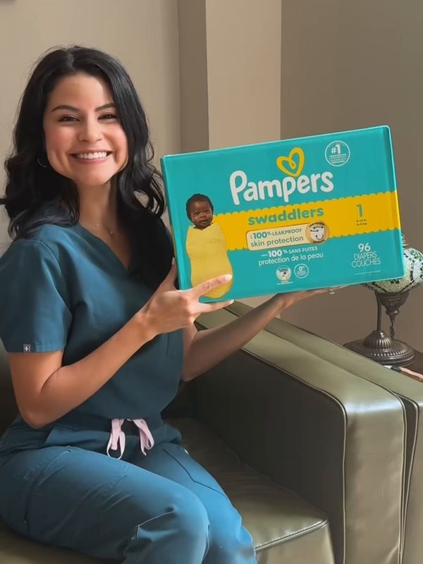 Andrea in scrubs holding a box of Pampers Swaddlers diapers